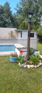 a lamp post and flowers in a yard with a pool at La quinta de Hostal in Rosario +6 photos
