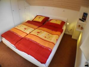 a bedroom with a large bed with red and orange blankets at Auszeit - Nordhorn in Nordhorn