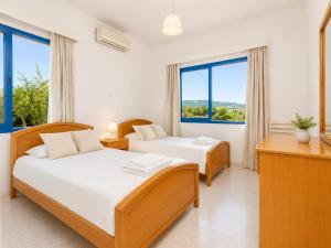 two beds in a room with two windows at Villa Charoula Ena Large Private Pool AC WiFi in Polis Chrysochous