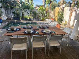 a wooden table and chairs in a patio with a pool at Plage 200m in Saint-Cyr-sur-Mer