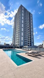a large building with a swimming pool in front of a building at Apartamento completo Studio 9 centro Pouso Alegre in Pouso Alegre