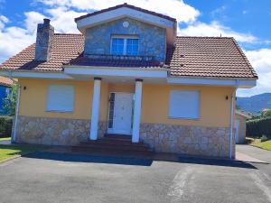 a yellow house with a stone wall at VV Las Picarolas in Muros de Nalón