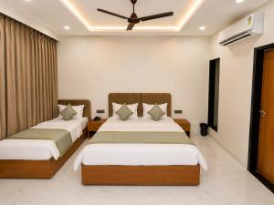 two beds in a hotel room with a ceiling fan at Hotel Heera Palace in Khātu