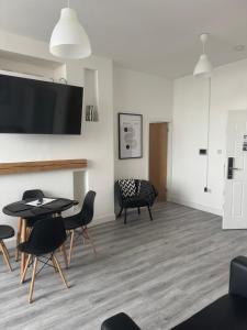 a living room with a table and chairs and a tv at Stylish modern 2 bedroom flat 6B in Denton