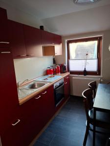 a kitchen with red cabinets and a sink and a window at Ferienwohnung in Walsrode