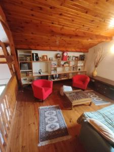 a living room with red chairs and a wooden ceiling at Los jardines de Osseja in Osséja