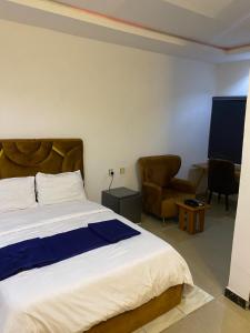 a bedroom with a large bed and a chair at Miad Hotels in Port Harcourt