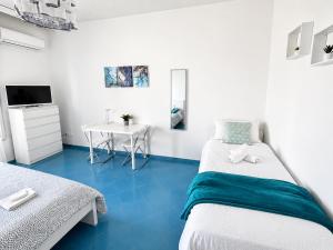 a room with two beds and a table with a television at Vista Mare, Netflix & AC - Smeraldo Apartment in Laigueglia
