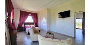 a hotel room with a bed and a living room at L'Oasis in Mzerguia