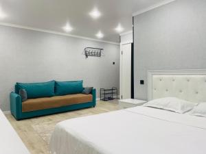 a bedroom with a bed and a blue couch at Elegant Home Apart in Karagandy