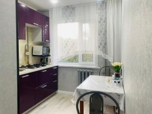 a kitchen with purple cabinets and a table and a window at Elegant Home Apart in Karagandy