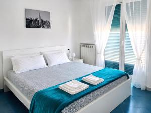 a white bedroom with a bed with towels on it at Vista Mare, Netflix & AC - Smeraldo Apartment in Laigueglia