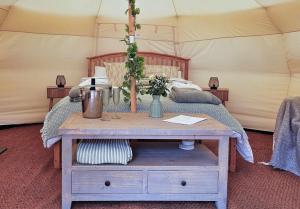 a bed in a tent with a table with flowers on it at Roden Retreat in Aston