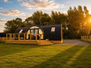 a small black cabin with a porch and a fence at Leisure Lodges in Glastonbury
