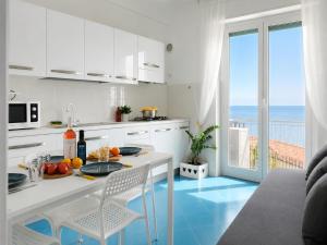 a kitchen with a table and chairs with a view of the ocean at Vista Mare, Netflix & AC - Smeraldo Apartment in Laigueglia