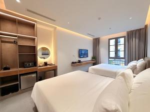 a hotel room with two beds and a television at Sunday Boutique Hotel in Phú Quốc