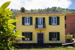 a yellow house with green shutters and a balcony at Vita Lenta in Biassa
