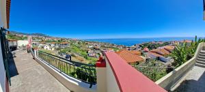 a balcony with a view of a town and the ocean at Pôr do Sol in Estreito da Calheta