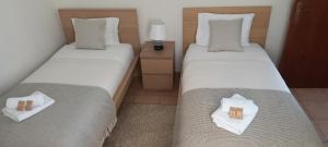 two twin beds in a room with towels on them at Pôr do Sol in Estreito da Calheta