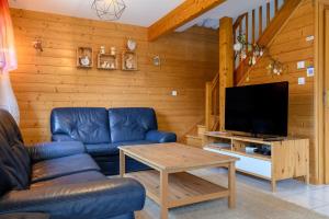 a living room with a couch and a tv at Chalet Les Genêts 2 - Spa et Sauna in Saint-Amarin