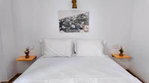 a bedroom with a bed with white sheets and two tables at To Nisi in Loutraki