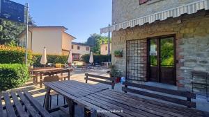 a patio with wooden benches and tables in front of a building at Da Carlo in Pietralunga +2 photos
