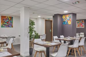 a dining room with tables and white chairs at Appart'hôtel Odalys City - Toulouse Centre Gare in Toulouse