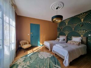 a bedroom with two beds and a blue door at Le Logis de Placide in Tarbes