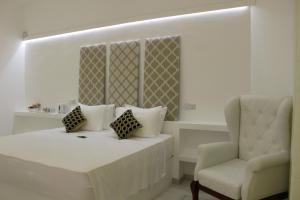 a bedroom with a white bed and a chair at Heaven By O in Unawatuna