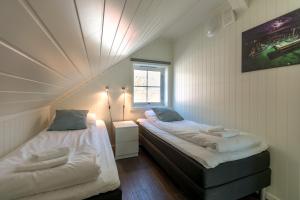 two beds in a small room with a window at Lofoten Rorbu Lodge in Offersøya