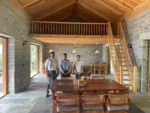 three men standing in a room with a wooden table at Devshal Eco-Stays in Gupta Kāshi