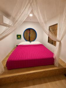 a bedroom with a large bed with a pink bedspread at Mojarra Beach-Wind Room- Santa Veronica in Salina de Rey