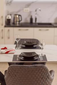 a table with two glasses and a plate and a chair at Vujicic Premium Suite in Tivat