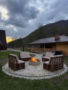 a fire pit in a yard with two chairs and a fire place at LaMonte Retreat in Brezoi