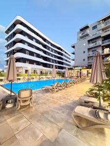 a pool with chairs and umbrellas in front of a building at Hotel Apart Resilient in Golem