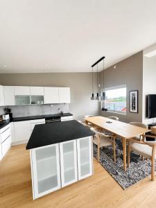 a kitchen and dining room with white cabinets and a wooden table at Lux Apartment Gravdal in Gravdal +14 photos