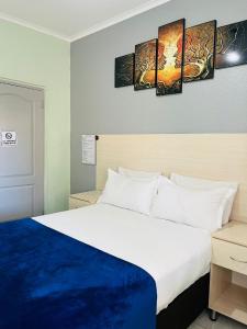 a hotel room with a bed and paintings on the wall at Ojong's Self Catering Accommodation Bellville in Cape Town +83 photos