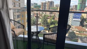 a balcony with a table and chairs and a view of a city at Serenity Spot - Cozy 1 bedroom with AC and Heater with City View in Nairobi, Westlands in Nairobi
