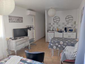 a living room with a television and a table with chairs at Ingrid Mary in Nîmes