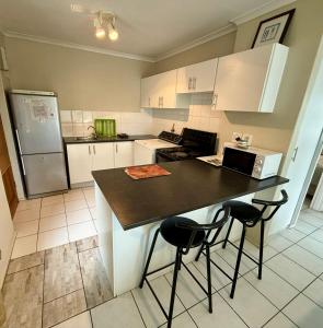 a kitchen with white cabinets and a black counter top at Serengeti Heide Self Catering Flats in Cape Town +10 photos