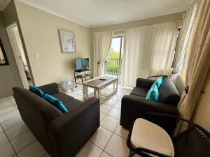 a living room with two couches and a television at Serengeti Heide Self Catering Flats in Cape Town