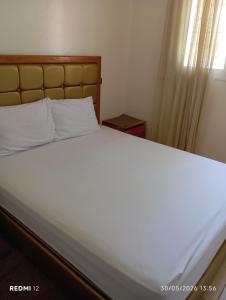 a bedroom with a large bed with white sheets and a window at Rez de chaussée in Ifrane