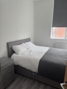 a bedroom with a bed and a dresser and a window at Stylish modern 2 bedroom flat 6B in Denton