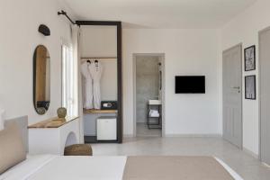 a white bedroom with a bed and a mirror at Pounda Resort Paros, a member of Radisson Individuals in Pounda