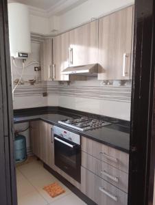 a kitchen with wooden cabinets and a stove top oven at Rez de chaussée in Ifrane