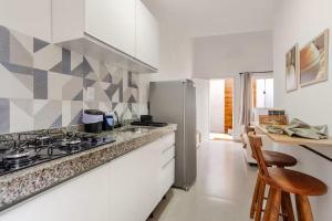 a white kitchen with a stove and a refrigerator at Villa Bela - Lofts - cama queen e ar-condicionado in Iguaba Grande