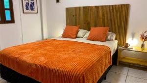 a bedroom with a large bed with an orange blanket at Pipa Surf House in Pipa