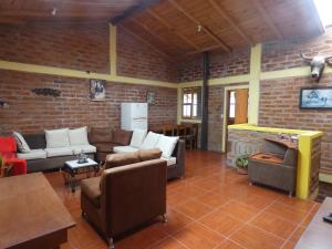 a living room with couches and a brick wall at Hostal el Vaquero in Chugchilán