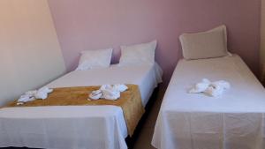 two beds in a room with white sheets and towels at hospedaria Cantinho da Rosa in Santo Amaro +3 photos
