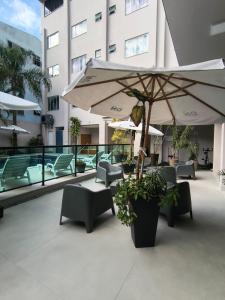 a patio with tables and chairs and an umbrella at Das Nações Hotel in Florianópolis